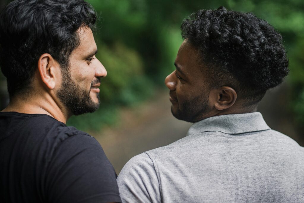 pexels photo 4833900 4833900 A close moment of affection between two men enjoying a walk in a lush, green outdoor setting.